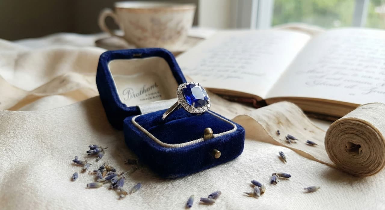 Cushion-cut sapphire halo ring in a vintage velvet box